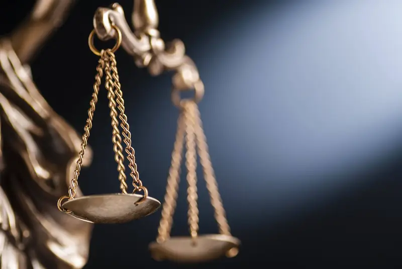 Balança da justiça em bronze sobre fundo azul